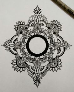 a drawing of a circular design on paper with a pencil next to it and a marker