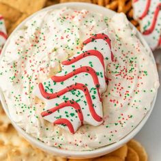 a white bowl filled with whipped cream surrounded by cookies and pretzel crackers