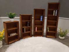 three wooden bookshelves sitting on top of a white rug