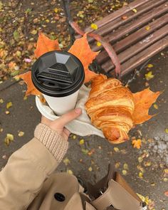 a person holding up a coffee cup and croissant