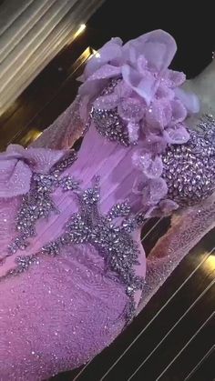 a purple dress with silver sequins and flowers on the bottom is sitting in front of a window