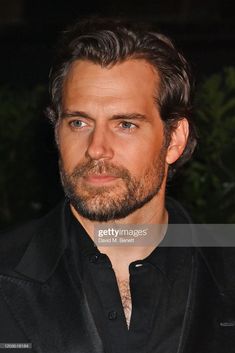 a close up of a man wearing a suit and black shirt