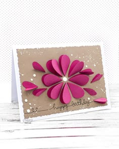 a handmade birthday card with pink paper flowers on the front, and white dots in the background