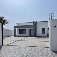 a white house sitting on top of a brick floor next to a tall fenced in area