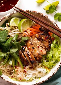 a bowl filled with meat and vegetables next to chopsticks on top of a table