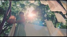 a woman standing in front of a canopy with the sun shining through her clothesline