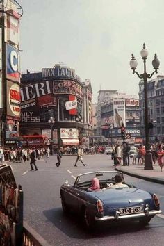 an old car driving down a busy city street