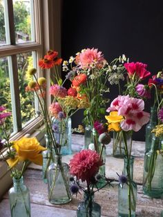 several vases filled with different colored flowers on a window sill