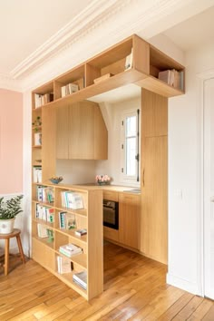 an open book shelf in the middle of a room with wooden floors and pink walls