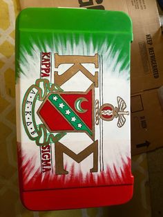 a green and red lunch box with the letter k on it's front side