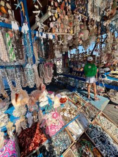 a man standing in front of a store filled with lots of necklaces