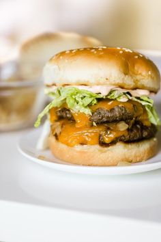 a cheeseburger with lettuce and other toppings on a white plate