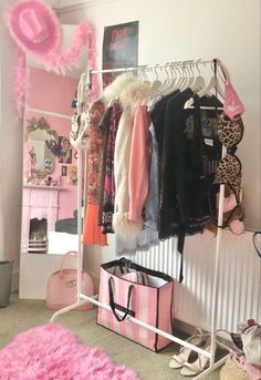 a pink and white closet with clothes hanging on the rack, purses and shoes