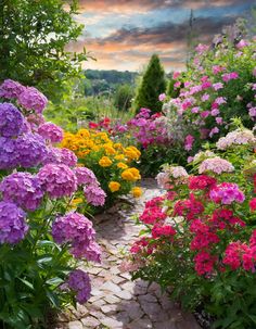 colorful flowers are blooming along a path in the middle of a garden at sunset