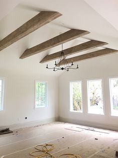 an empty room with three windows and some beams in the ceiling that have been painted white