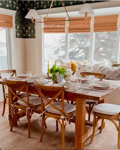 a dining room table set with place settings and flowers in vases on the table