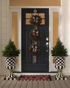 two planters with christmas wreaths on them sitting in front of a door