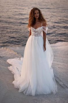 a woman in a wedding dress standing on the beach