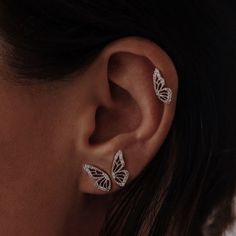 a close up of a woman's ear with two butterfly shaped earrings on it