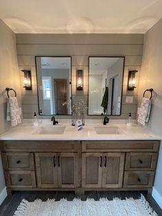 a bathroom with two sinks, mirrors and lights on the wall above it's counter