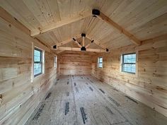 an empty room with wooden walls and windows in the center is made of wood planks