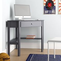 a computer desk with a laptop on top of it next to a blue rug and basketball