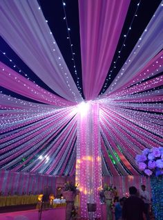 the ceiling is decorated with pink and white lights for a wedding or special occasion at night