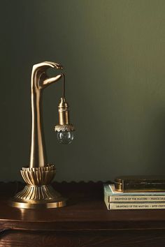 a golden faucet on a wooden table next to some books and a lamp