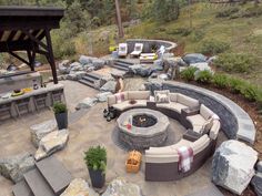 an outdoor fire pit surrounded by rocks and seating area with chairs, tables and couches