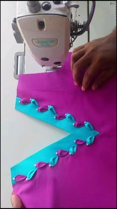 someone is using a sewing machine to sew something on the fabric with blue stitching