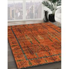 an orange rug in a living room with cityscape and plants on the floor