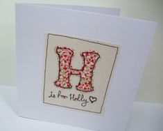 a white card with the letter h in red and pink flowers on it's front