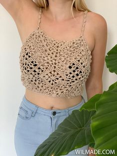 a woman wearing a crochet crop top and denim shorts with her hand on her hip