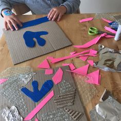 a young boy is making some paper cutouts with scissors and tape on the table