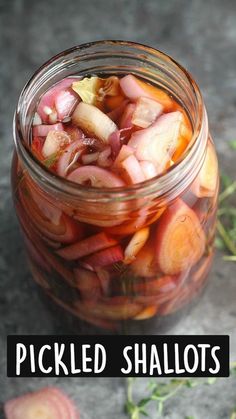 a jar filled with sliced up vegetables sitting on top of a stone counter next to herbs