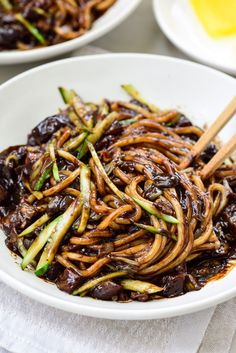 a white bowl filled with stir fry vegetables and chopsticks on top of a table