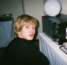 a young man sitting in front of a microwave on top of a white table cloth