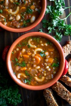 two bowls filled with soup next to some bread