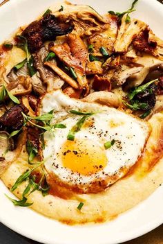 an egg is sitting on top of grits in a white bowl with mushrooms and spinach