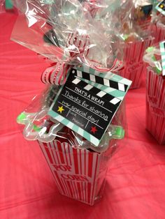 popcorn boxes with movie claps on them sitting on a red cloth covered tablecloth