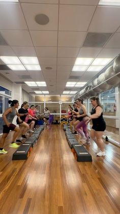 a group of people running on treadmills in a room with hard wood floors