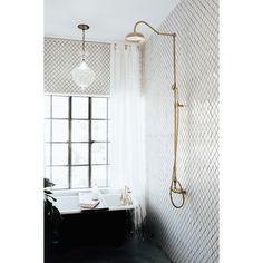 a bath tub sitting next to a window with curtains on the windowsill and a shower head