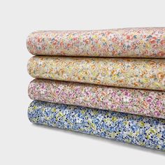 four floral fabrics stacked on top of each other in different colors and sizes, with one folded