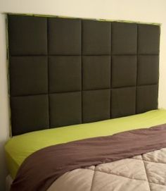 a bed with a green headboard and brown sheets