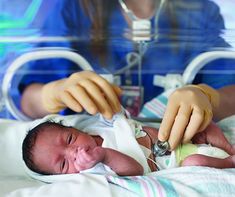 a baby is being held in an inclosure by two medical gloves on it's hands