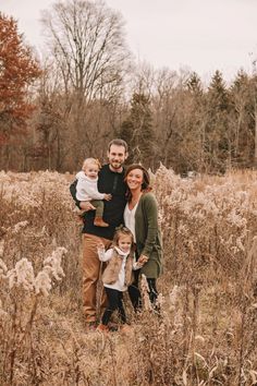 a family poses for a photo in the middle of a field with tall grass and trees