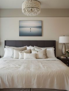 a bedroom with a large bed, chandelier and paintings on the wall above it