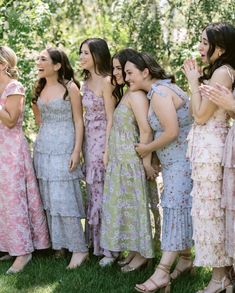 a group of women standing next to each other on top of a lush green field