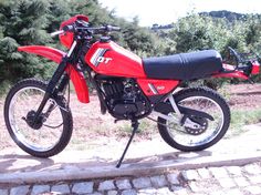 a red dirt bike parked on top of a sidewalk