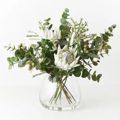 a vase filled with white flowers and greenery